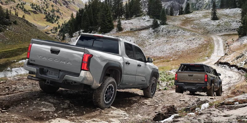 Two toyota trucks driving down a hill.