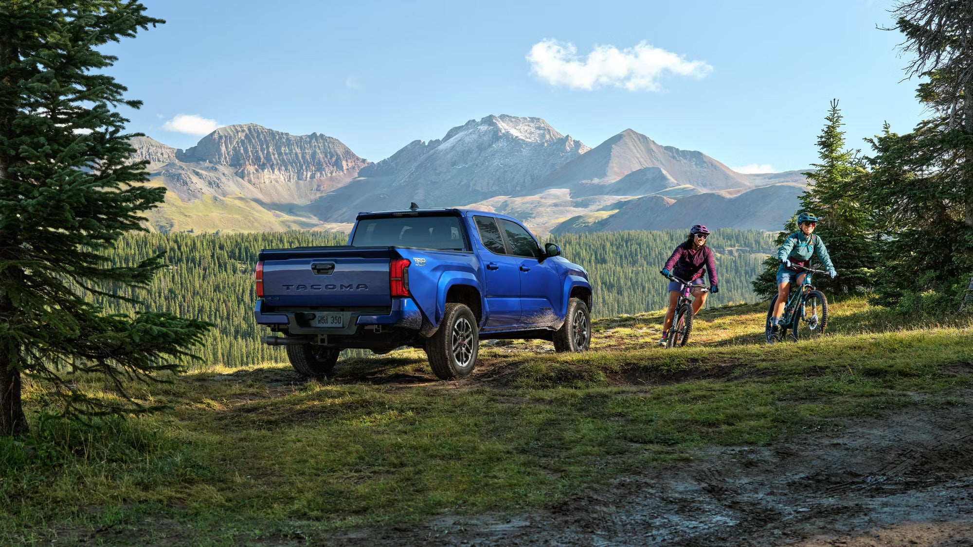Two people riding bikes around a blue truck.