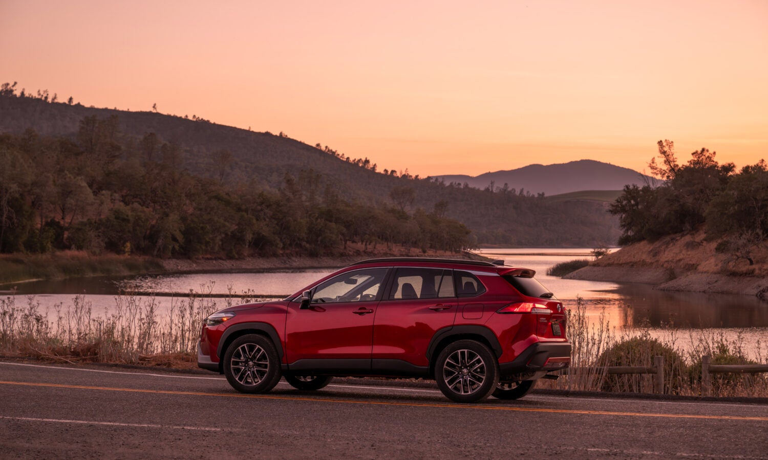 2026 corolla cross driving with a river in the back ground