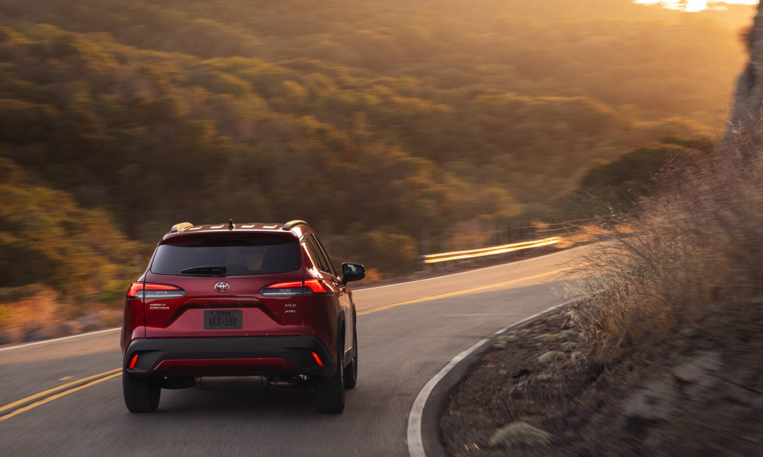 a red toyota corolla cross driving in the country side