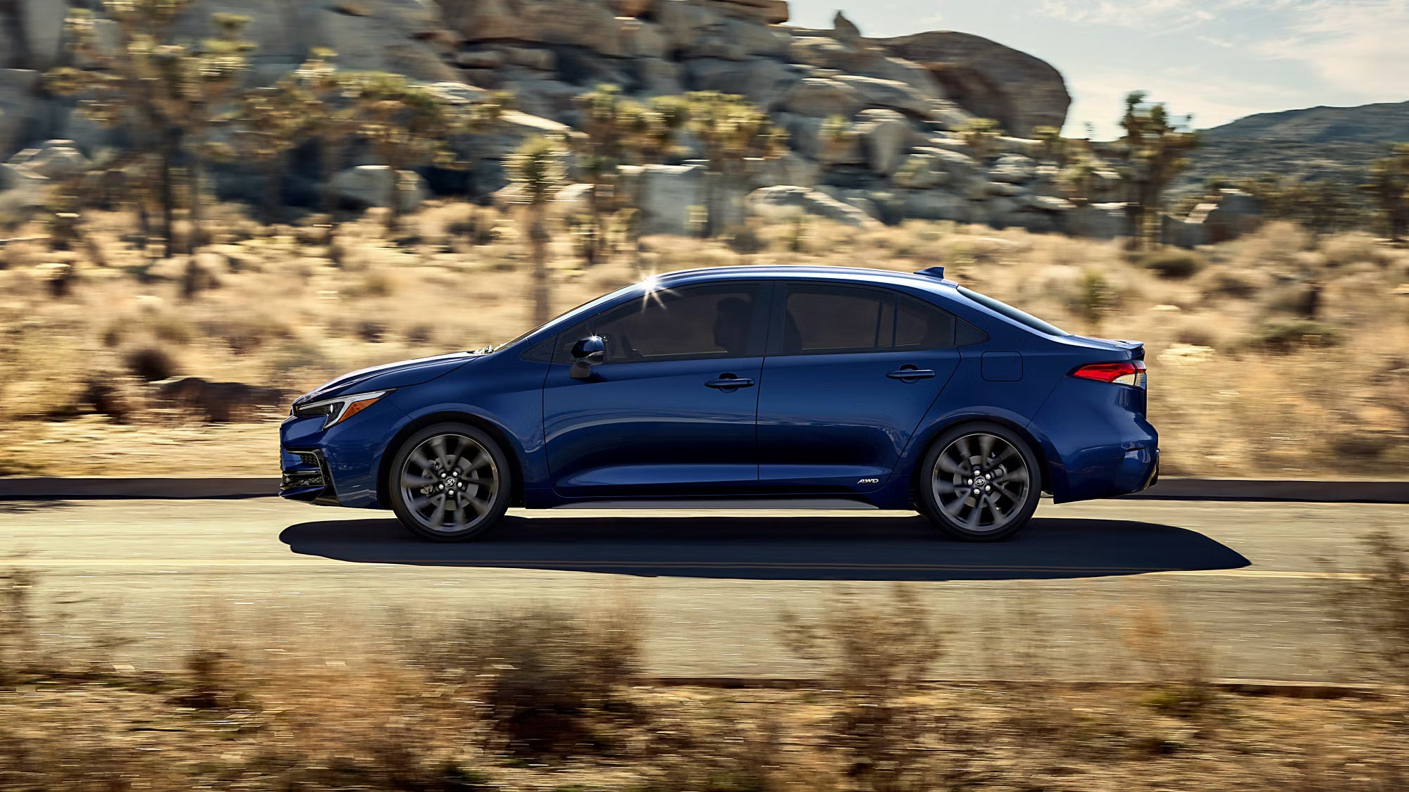 a blue toyota corolla driving in the desert