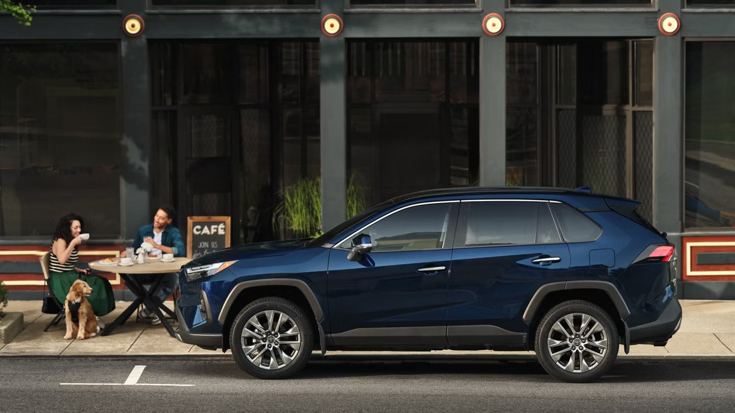 a blue 2025 toyota rav4 parked in front of a cafe building