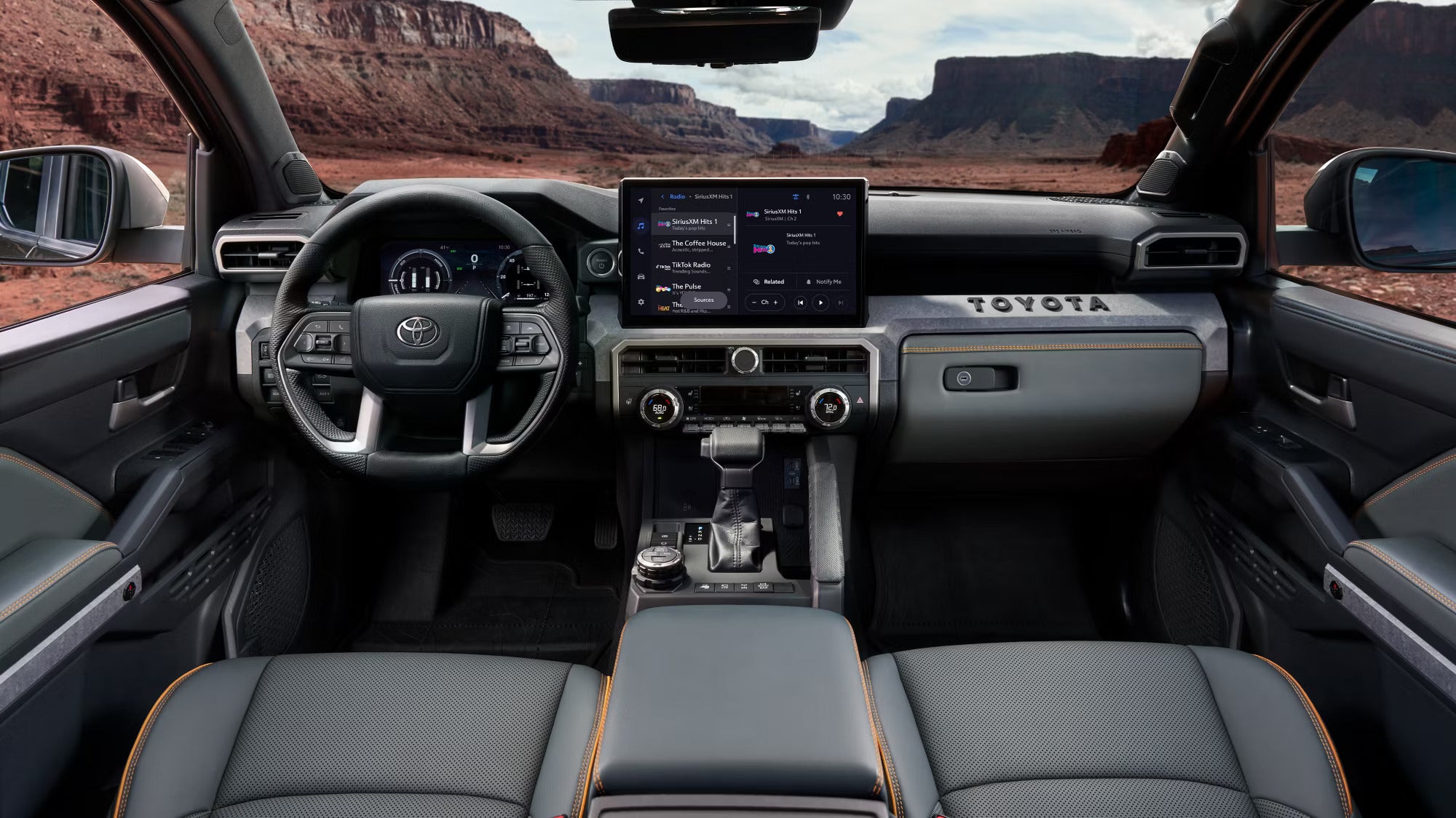 2025 Toyota Tacoma interior showcasing modern dashboard, large touchscreen display, and canyon views through the windshield.
