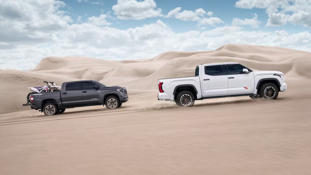 Two 2025 Toyota Tundra trucks driving through the desert, showcasing their rugged off-road capabilities