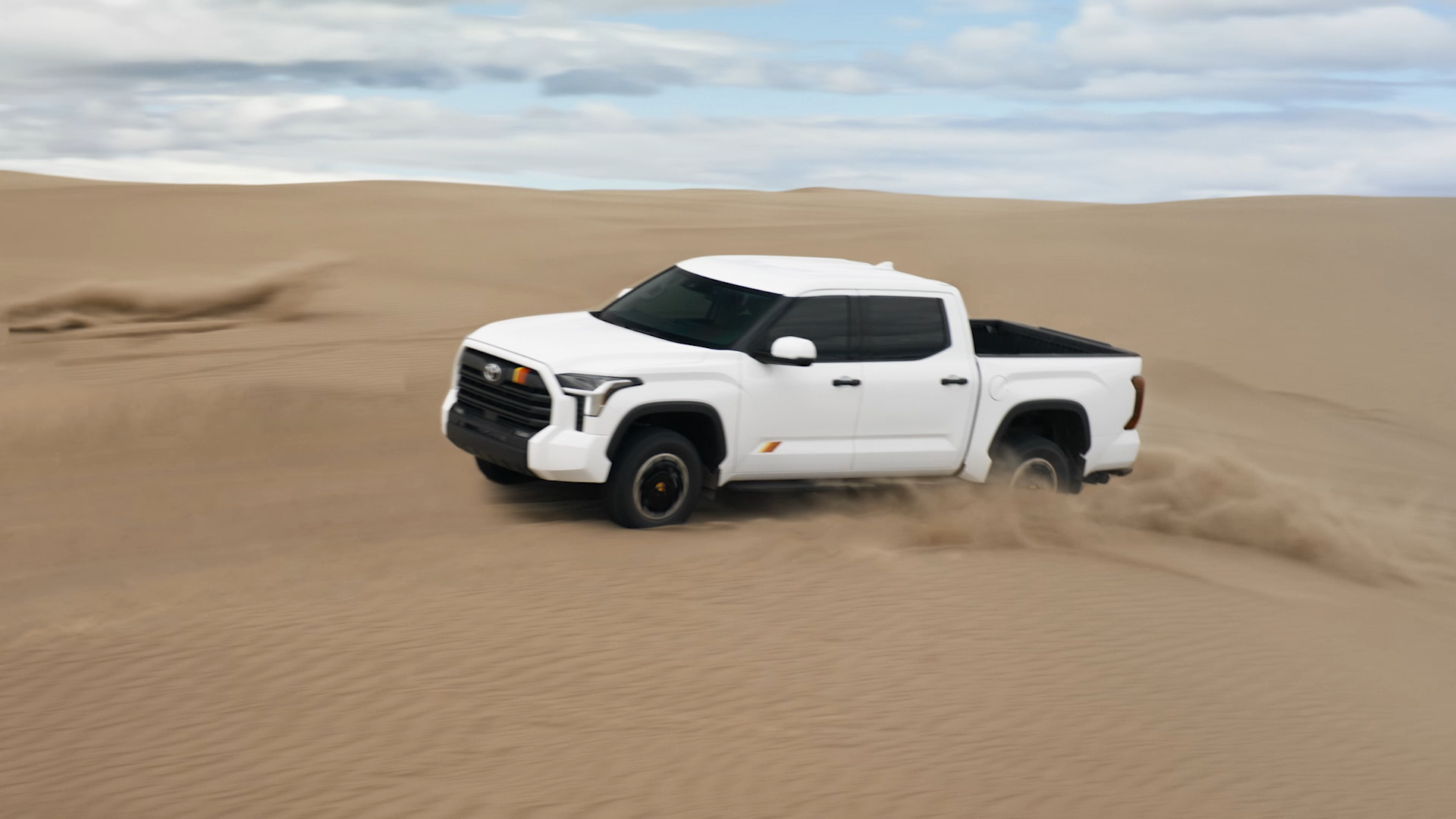 2025 Toyota Tundra driving through desert dunes showcasing its off-road capability