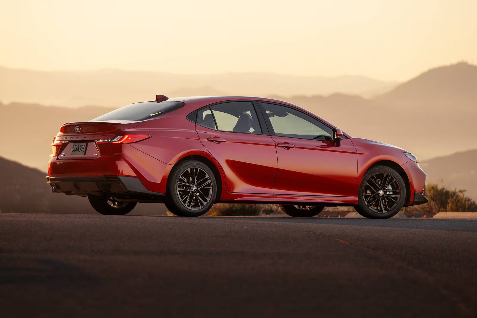 A red car sitting parked on the road.