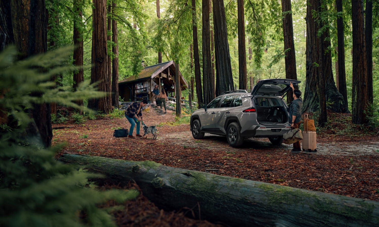 Two peopel around a siver suv in the woods.
