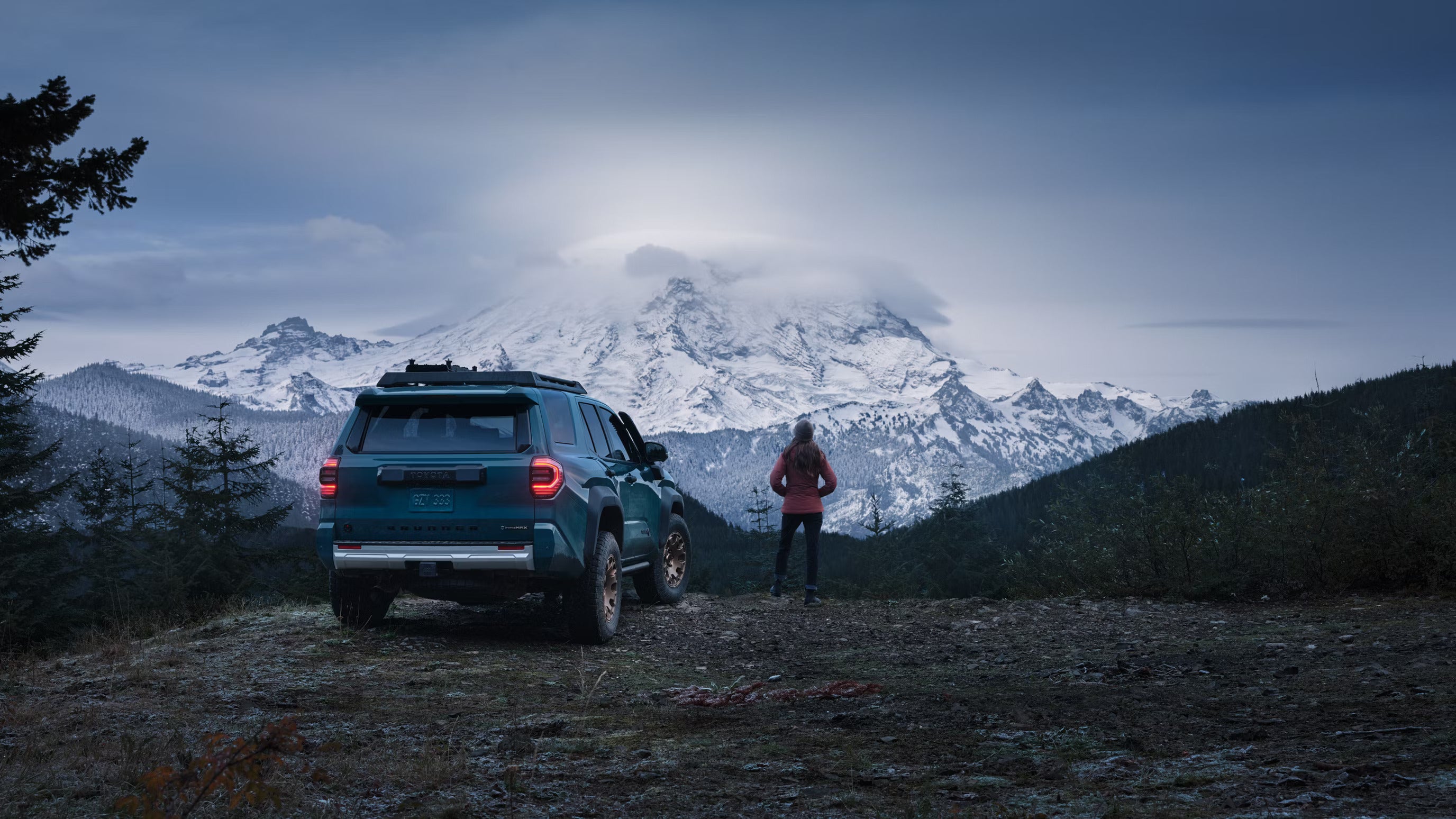 A woman standing next to a blue suv.